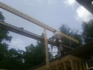Carpenter setting a ridge beam over a new addition frame — Ice Dam Removal by Roofing Brothers in Shubuta