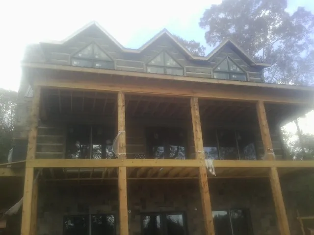 Dormers and porch framing on a large log home under construction — Roof Coating work by our crew in Shubuta