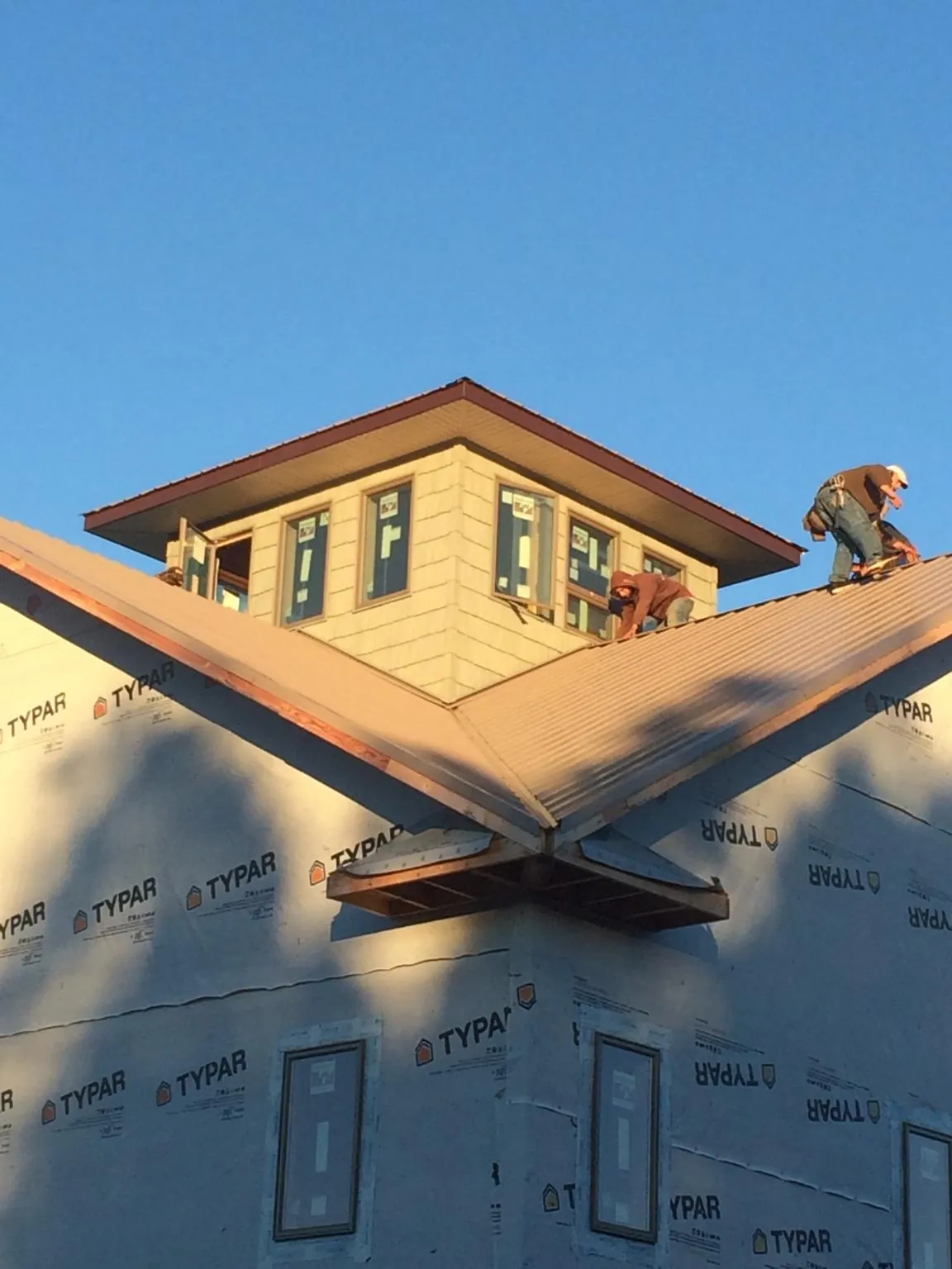 Roofers working around a rooftop cupola on a new metal roof at sunset — Roof Waterproofing in Shubuta by Roofing Brothers